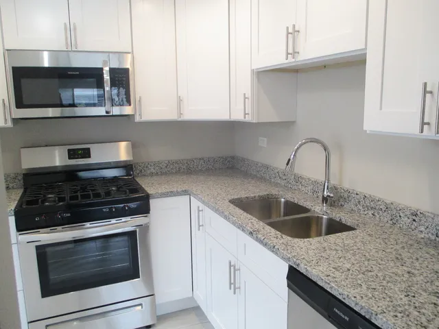 a kitchen with granite countertop a sink stainless steel appliances and cabinets