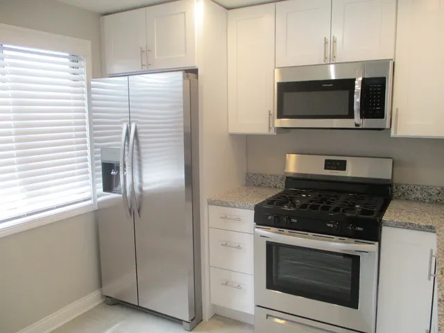 a kitchen with stainless steel appliances granite countertop white stove a microwave and a window