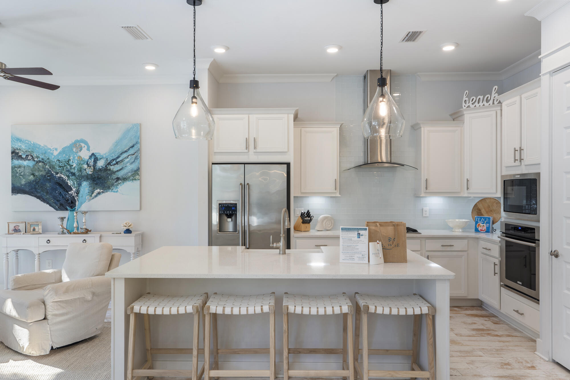 a kitchen with stainless steel appliances kitchen island granite countertop a sink a stove a refrigerator and white cabinets with wooden floor