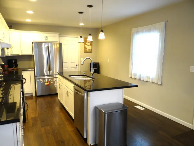 a kitchen with stainless steel appliances granite countertop a sink a stove and a refrigerator