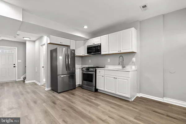 a kitchen with a refrigerator sink and white cabinets