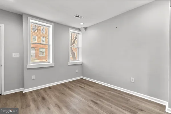 an empty room with wooden floor and windows