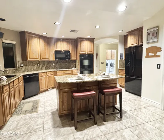 a kitchen with stainless steel appliances kitchen island granite countertop a refrigerator and a stove top oven