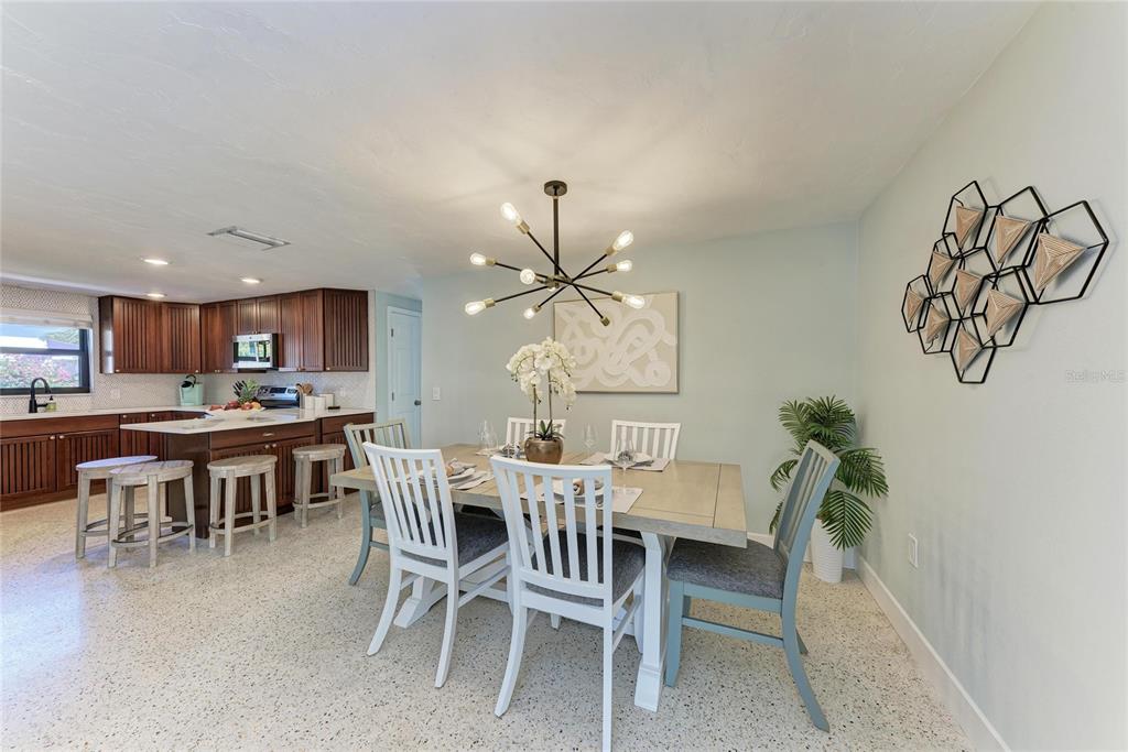 730 Fox Street Longboat Key, FL 34228 - Photo 12 of 40 a dining room with wooden floor a chandelier a wooden table and chairs