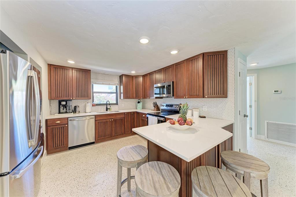 730 Fox Street Longboat Key, FL 34228 - Photo 16 of 40 a kitchen with a refrigerator a stove top oven a sink dishwasher and white cabinets with wooden floor