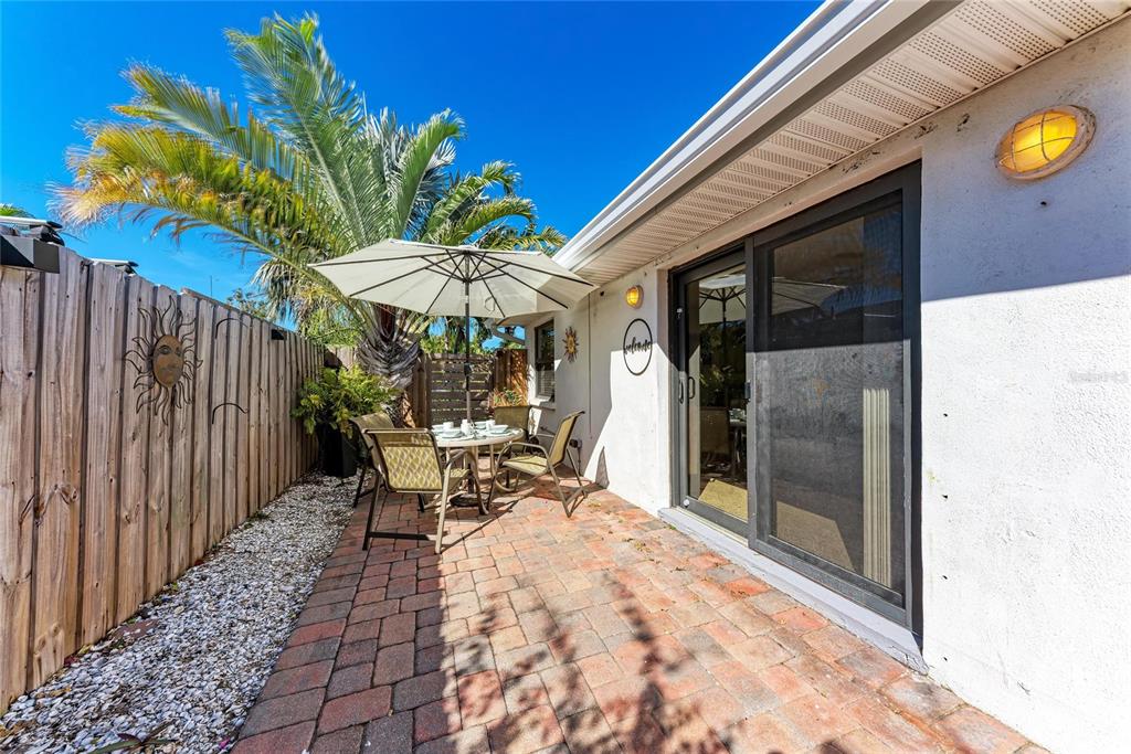730 Fox Street Longboat Key, FL 34228 - Photo 33 of 40 a view of a patio with table and chairs under an umbrella with wooden fence