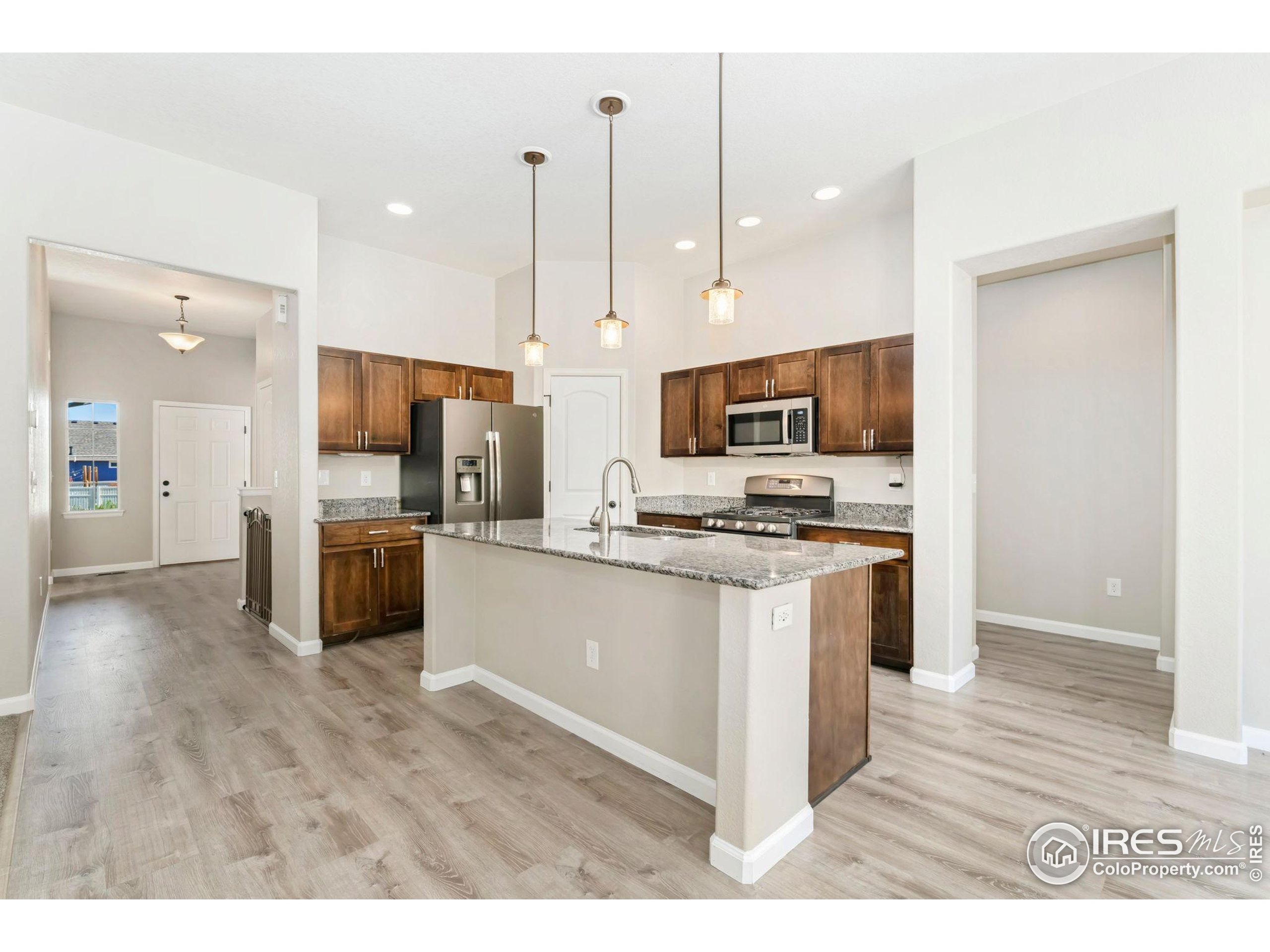 11449 Coal Ridge Street Firestone, CO 80504 - Photo 2 of 33 a kitchen with stainless steel appliances kitchen island granite countertop a refrigerator a sink a stove and oven