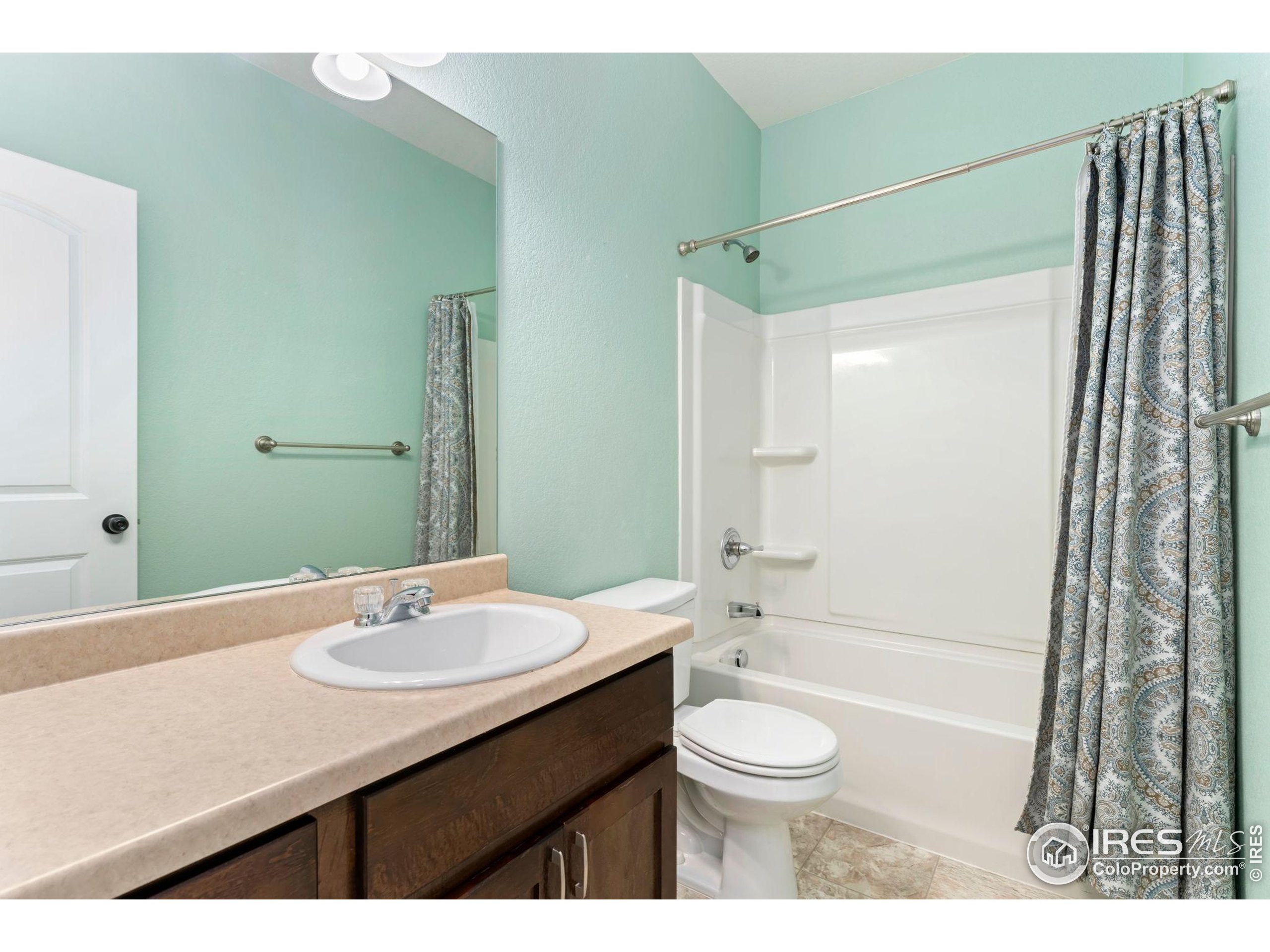 11449 Coal Ridge Street Firestone, CO 80504 - Photo 23 of 33 a bathroom with a sink a toilet a mirror a bathtub and shower