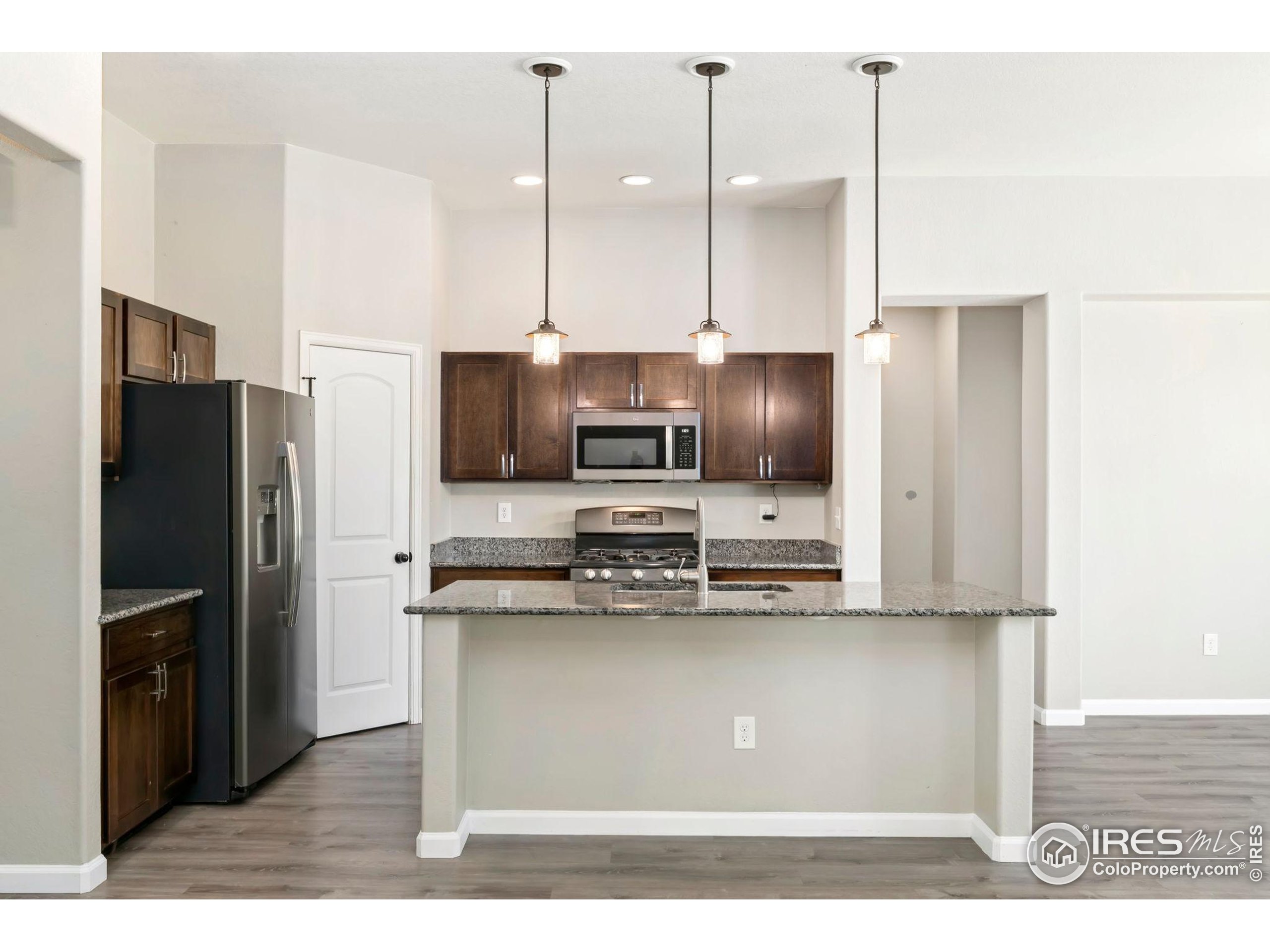 11449 Coal Ridge Street Firestone, CO 80504 - Photo 5 of 33 a kitchen with stainless steel appliances a refrigerator a stove a sink and white cabinets