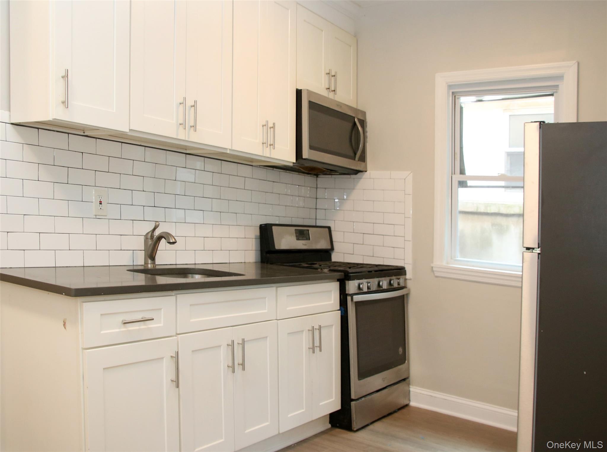 104-07 177th Street Queens, NY 11433 - Photo 13 of 19 a kitchen with stainless steel appliances white cabinets and a sink