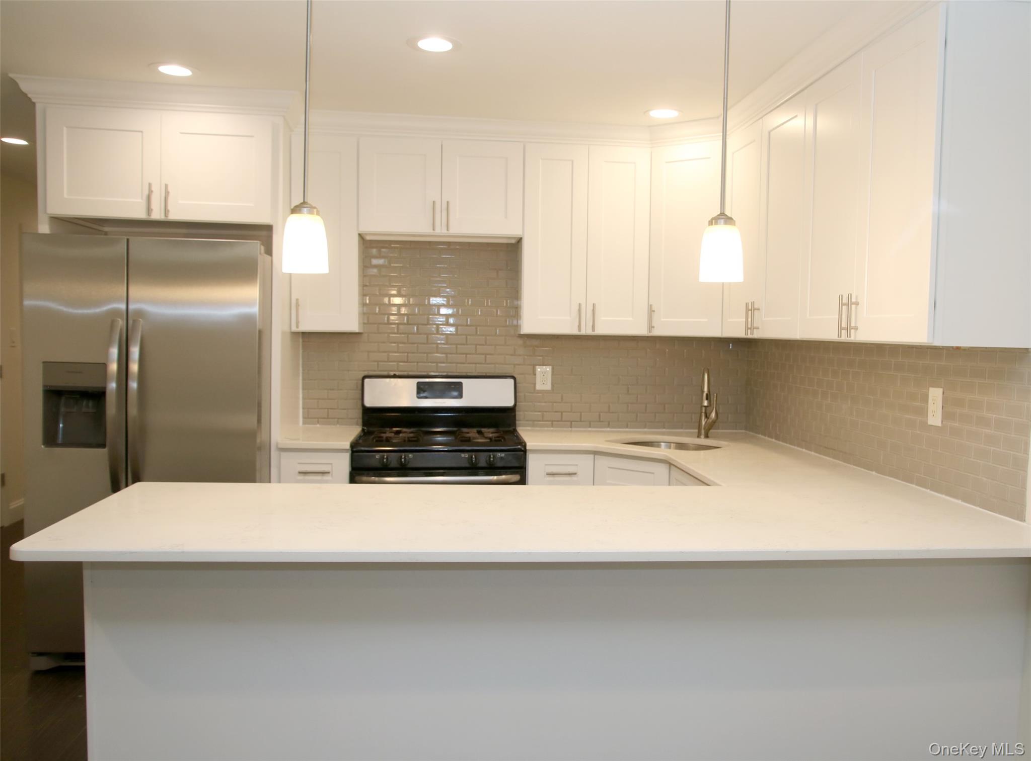 104-07 177th Street Queens, NY 11433 - Photo 5 of 19 a kitchen with stainless steel appliances a sink a stove a refrigerator and white cabinets