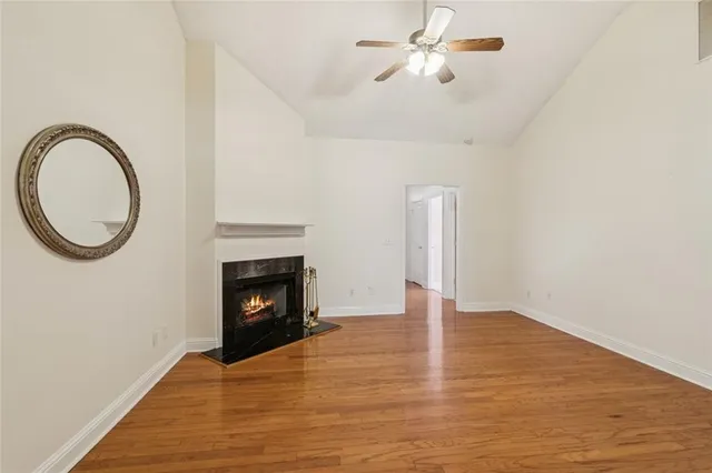 a view of an empty room with wooden floor and a fireplace