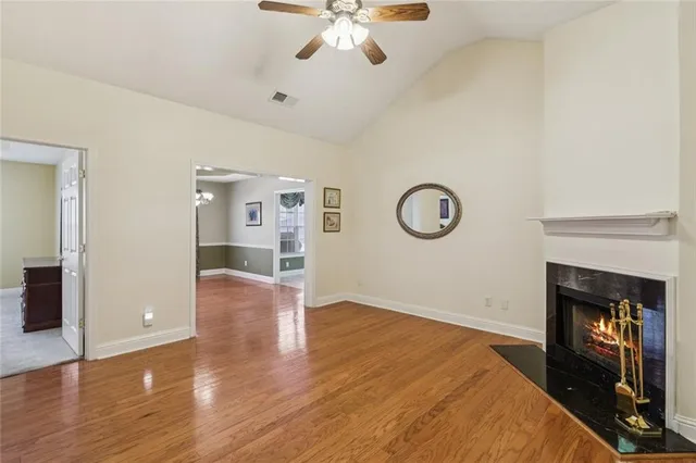a view of an empty room with wooden floor and a chandelier