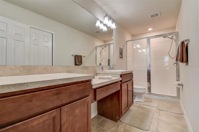a spacious bathroom with a granite countertop sink a toilet a mirror and shower