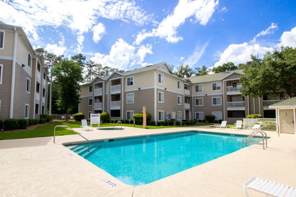 4000 Southwest 23rd Street, Unit 4104 Gainesville, FL 32608 - Photo 1 of 1 a building view with swimming pool and trees in the background