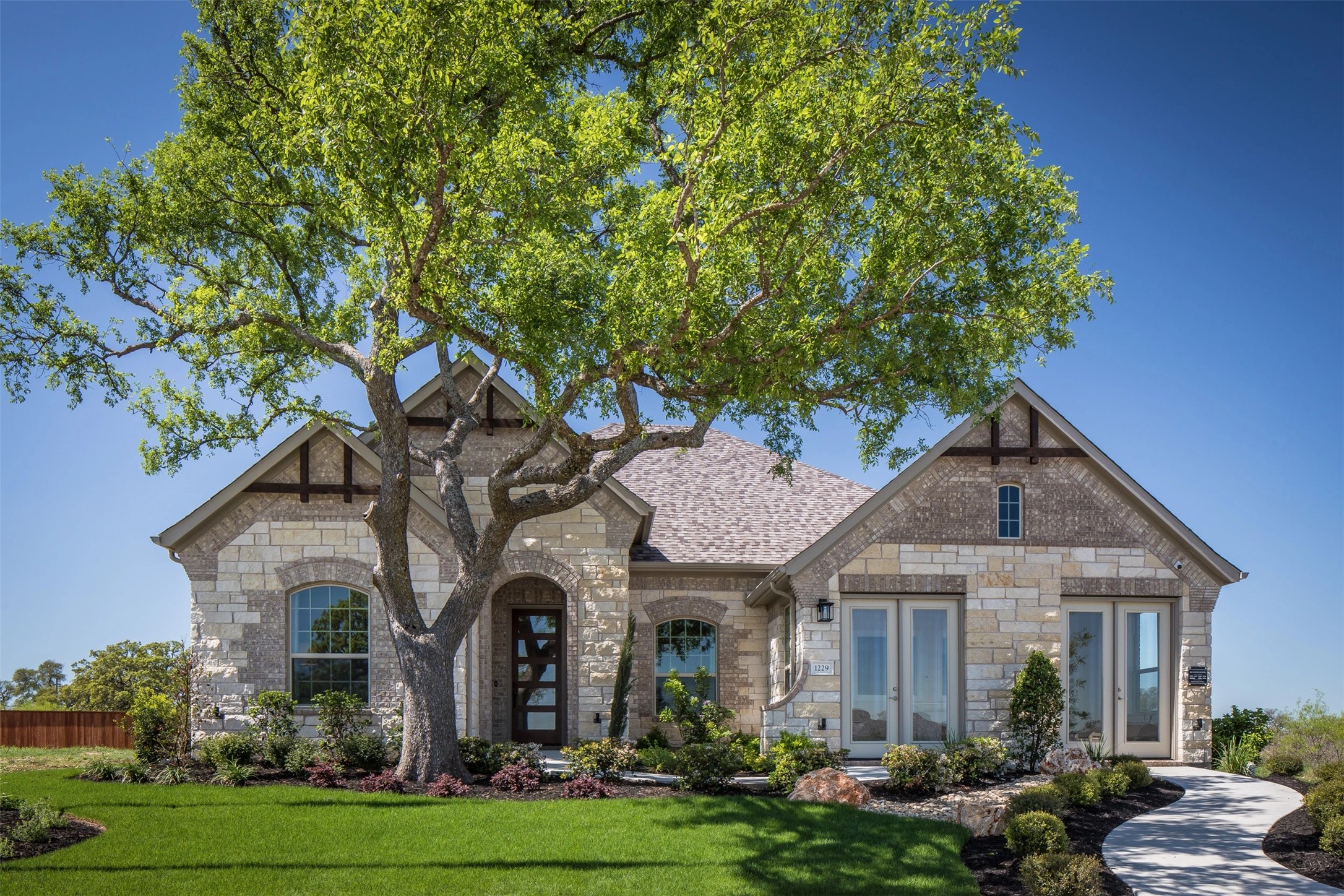 A graceful stone and brick facade welcomes you to this charming residence with mature landscaping and an inviting pathway.
