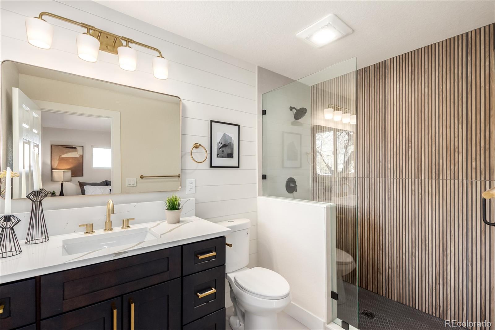 1760 South Dale Court Denver, CO 80219 - Photo 11 of 23 a bathroom with a sink a toilet a mirror a vanity and shower