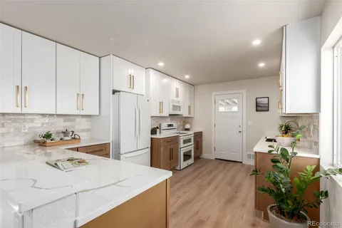 a kitchen with a sink dishwasher stove and white cabinets with wooden floor