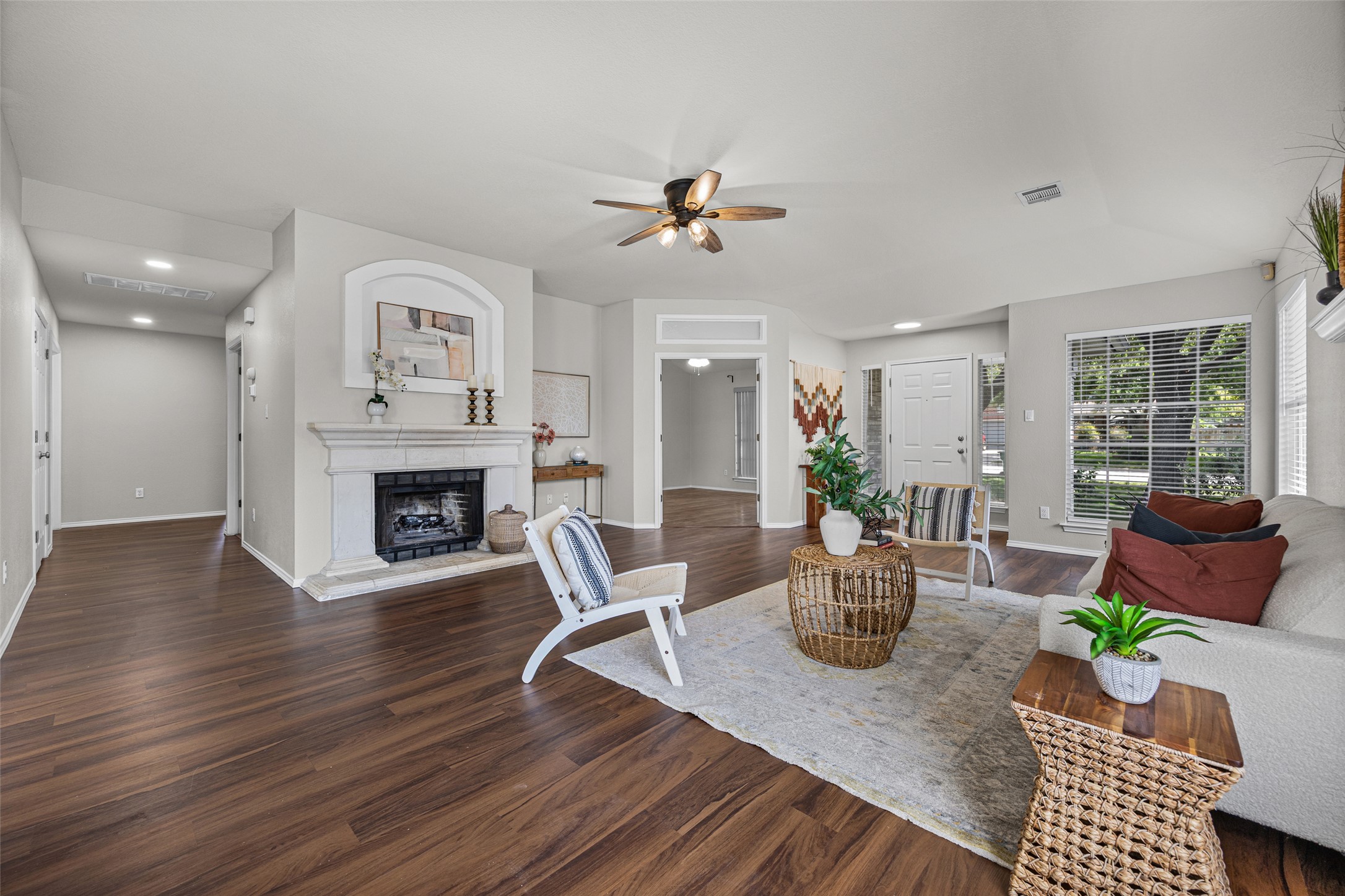 1524 Lochaline Loop Pflugerville, TX 78660 - Photo 7 of 22 A well-lit living area features a warm fireplace and rich wood flooring, perfect for relaxation.