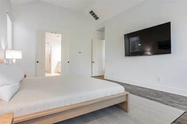 a bedroom with a bed a flat screen tv and guitar