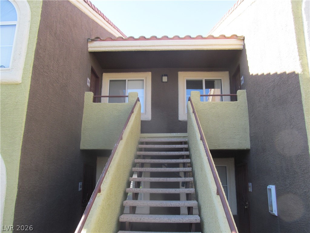7950 West Flamingo Road, Unit 2048 Las Vegas, NV 89147 - Photo 4 of 24 A terracotta-tiled roof crowns this multi-level residential facade, featuring an exterior stairway leading to upper units.