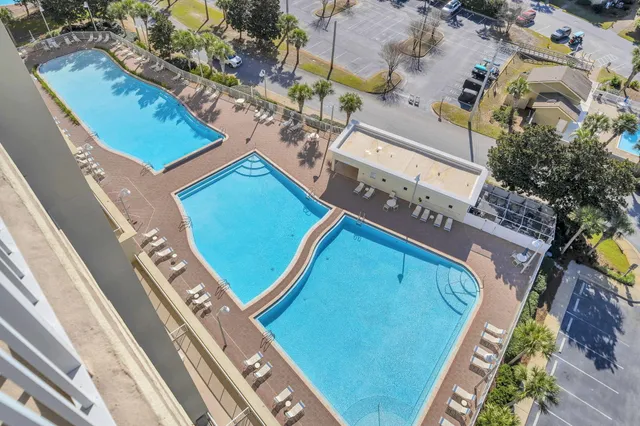 a view of a lake with a lawn chairs and large trees