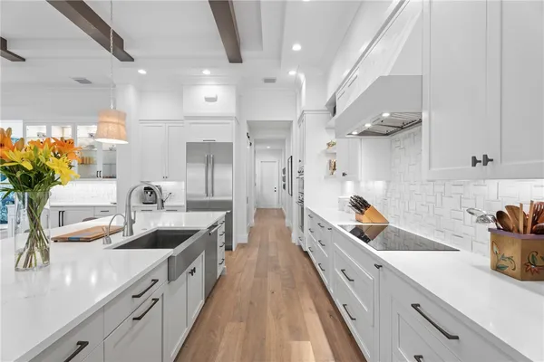 a kitchen with kitchen island granite countertop lots of white cabinets a sink dishwasher and a stove with wooden floor