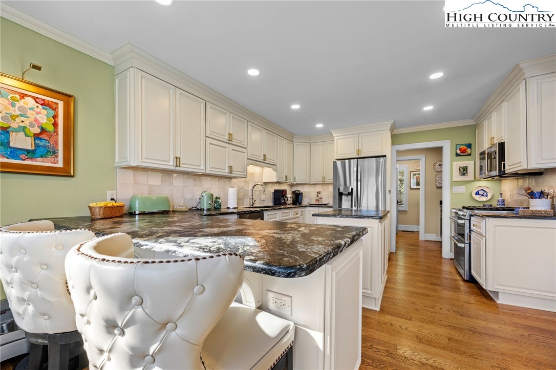 129 Valley View Road Blowing Rock, NC 28605 - Photo 12 of 45 a kitchen with stainless steel appliances granite countertop a sink a stove a refrigerator a microwave oven with white cabinets and wooden floor