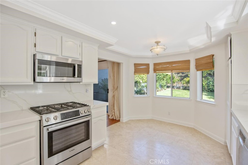 5974 Ruthwood Drive Calabasas, CA 91302 - Photo 3 of 30 a kitchen with stainless steel appliances a stove a microwave and white cabinets