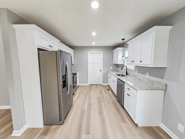 a kitchen with a sink a refrigerator and cabinets