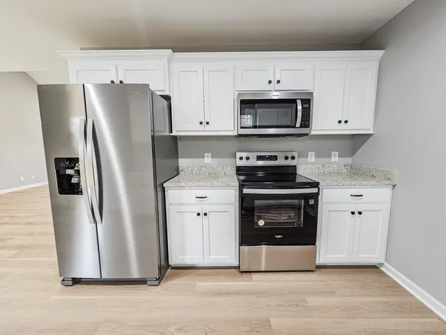 a kitchen with stainless steel appliances a refrigerator stove and white cabinets
