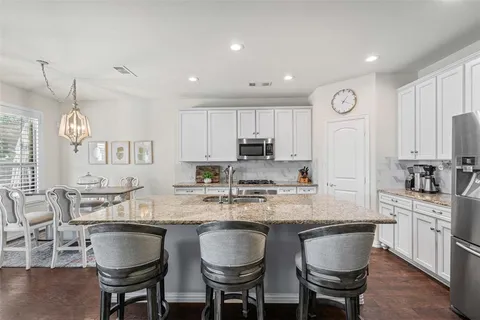 a kitchen with granite countertop white cabinets and stainless steel appliances