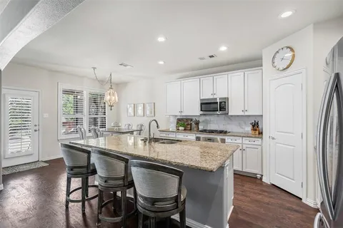 a kitchen with stainless steel appliances granite countertop a table chairs stove microwave and cabinets