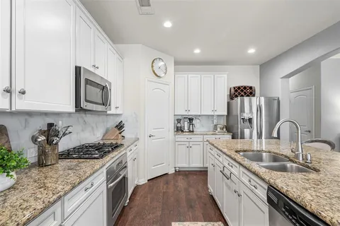 a kitchen with stainless steel appliances granite countertop a sink stove refrigerator and cabinets