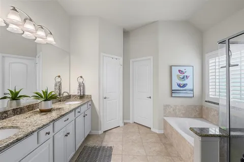 a spacious bathroom with a granite countertop tub a sink and a large mirror