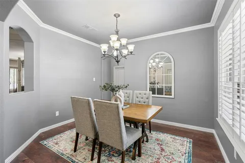 a dining room with chandelier and wooden floor