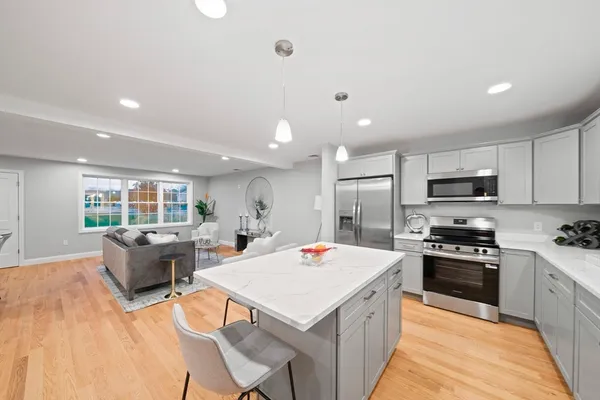 a large kitchen with kitchen island a stove a sink a refrigerator and a dining table with wooden floor