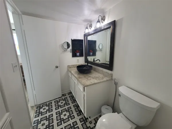 a bathroom with a granite countertop toilet and a sink