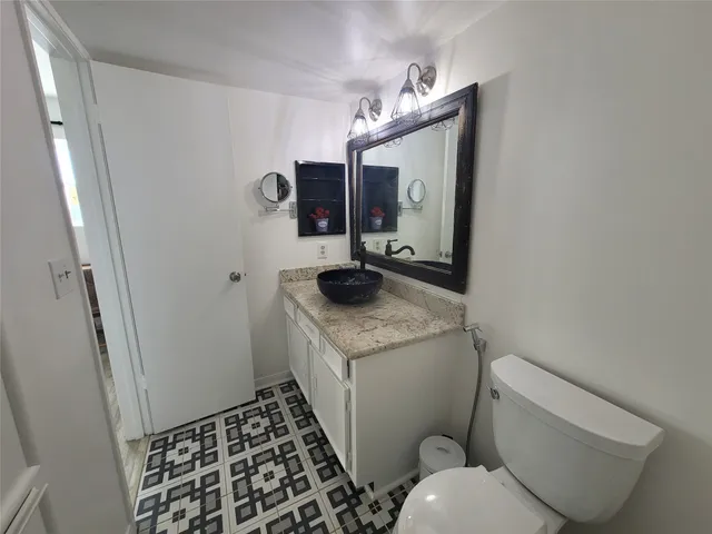 a bathroom with a granite countertop toilet and a sink