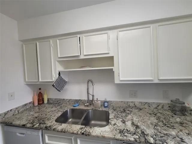 a kitchen with granite countertop a sink and cabinets