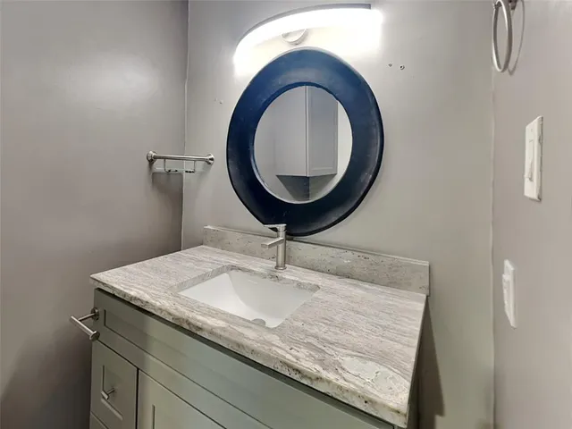 a bathroom with a granite countertop sink and a mirror
