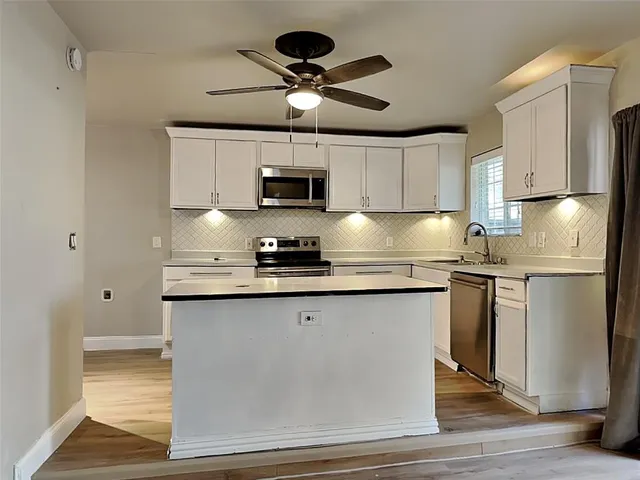 a kitchen with stainless steel appliances granite countertop a sink a stove a refrigerator cabinets and wooden floor