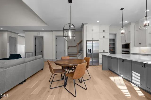 a kitchen with stainless steel appliances kitchen island granite countertop a dining table chairs and white cabinets