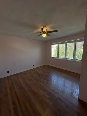 a view of an empty room with window and wooden floor