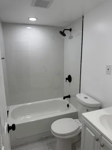 a white toilet and tub sitting next to a bathroom sink