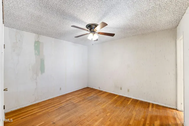 a view of empty room with wooden floor and fan