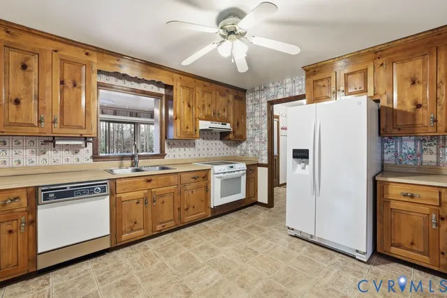 a kitchen with stainless steel appliances granite countertop a refrigerator a stove a sink and dishwasher with a dining table