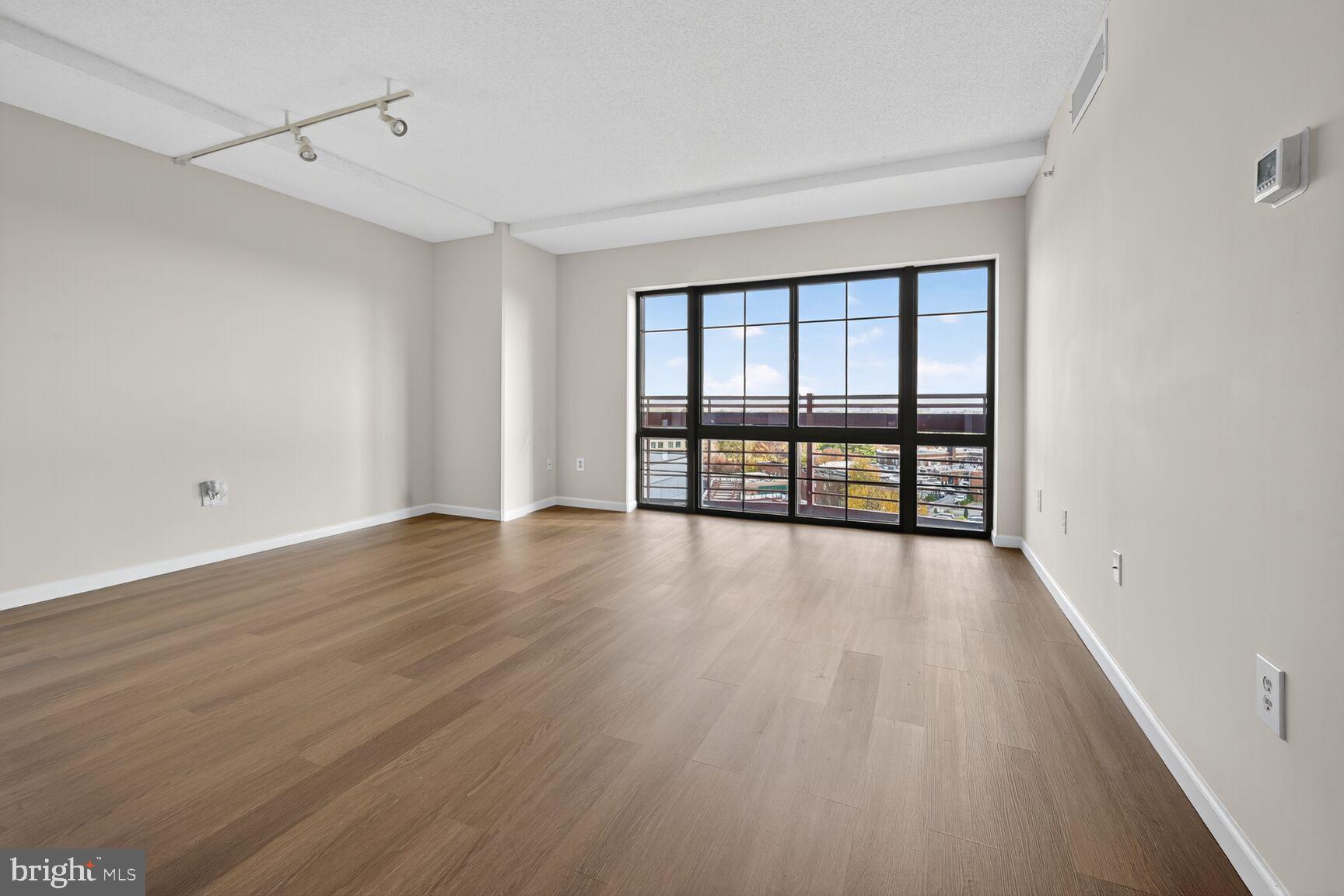 7915 Eastern Avenue Northwest, Unit 1114 Silver Spring, MD 20910 - Photo 7 of 34 a view of an empty room with a window and wooden floor