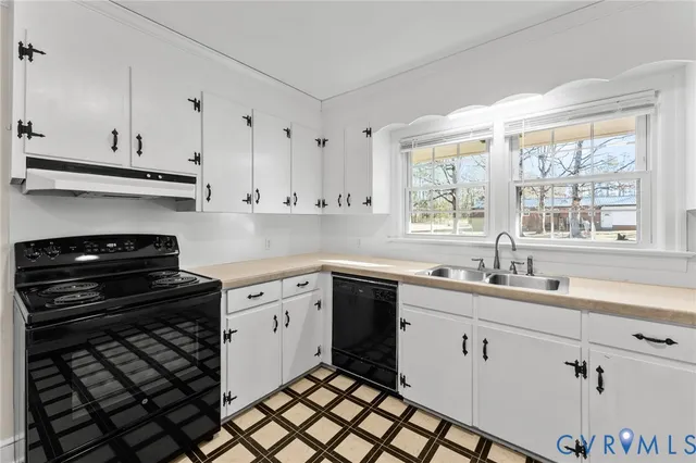 a kitchen with white cabinets a stove and a window