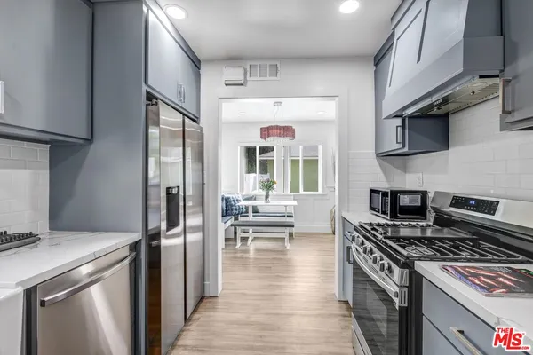 a kitchen with stainless steel appliances granite countertop a stove top oven a sink and a refrigerator